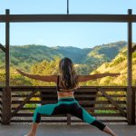 woman in black tank top and blue denim shorts sitting on brown wooden railings during daytime