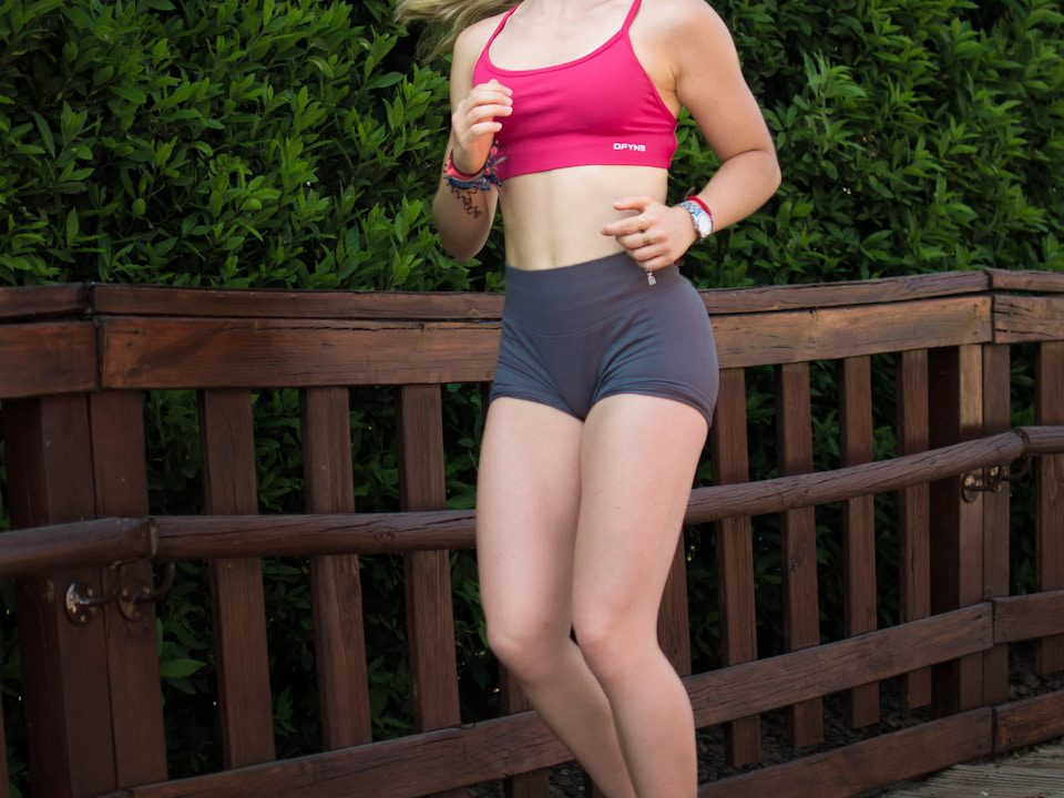 Young woman jogging on a wooden path outdoors.