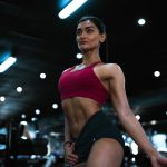 a woman in a red top and green skirt in a gym