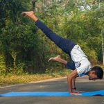 A man doing a handstand on a blue mat
