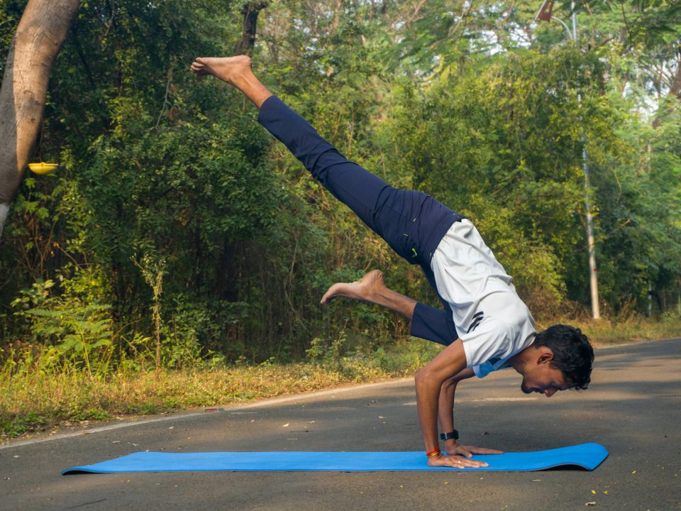 A man doing a handstand on a blue mat